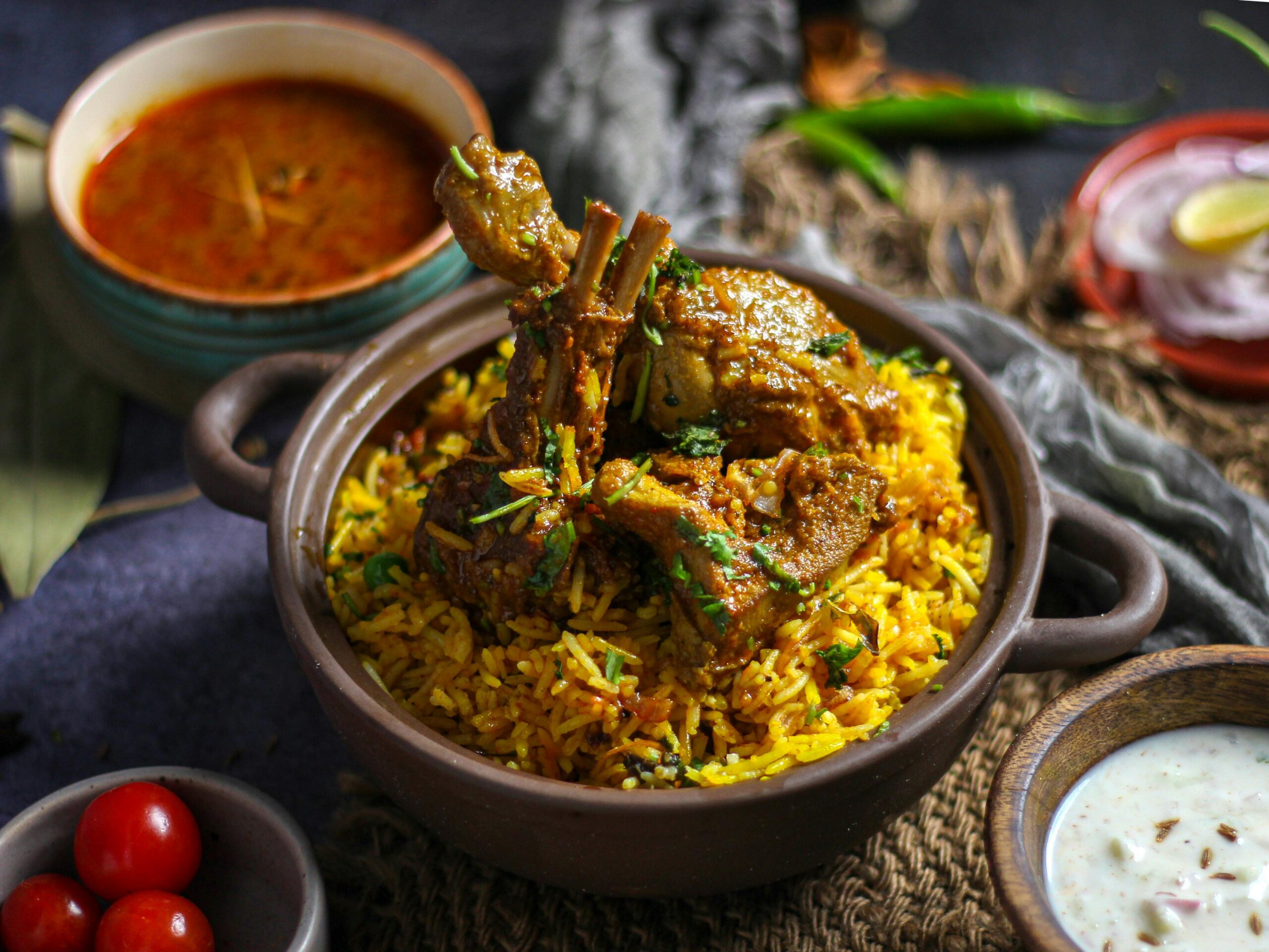 Delicious Indian lamb biryani served with spicy curry and yogurt sauce, perfect for a flavorful meal.
